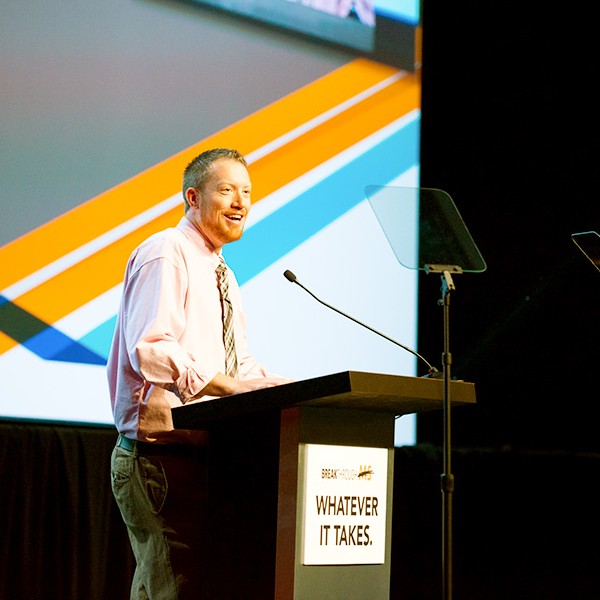 Brett Fling speaking behind a podium