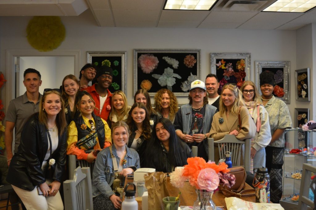 a large group photo of students with professor Chisholm, Professor Kissell, and the owner of the fabric flower shop