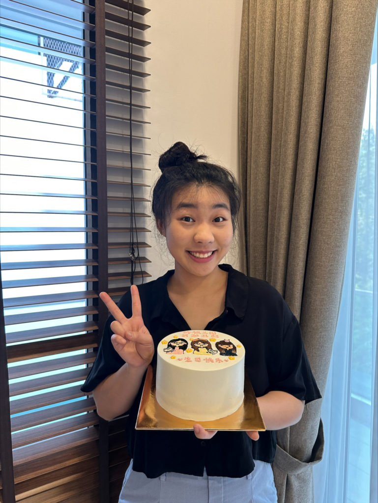 Ellie Tao is smiling holding a decorative cake