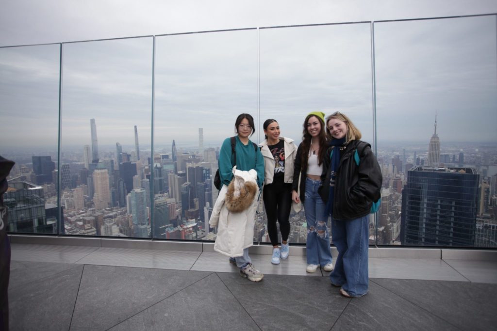 IAD students stand on top of a building with a city view behind them