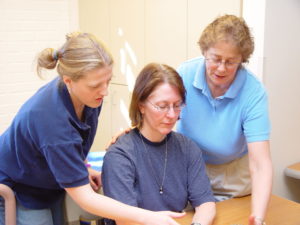 Two people assisting a third person in an occupational therapy course