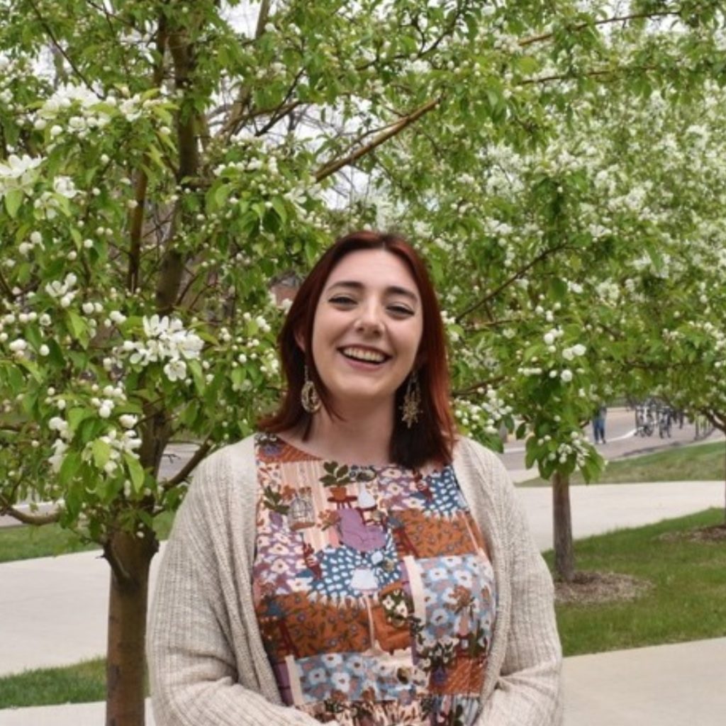 Lynsey Fenter smiles next to a blossom tree.