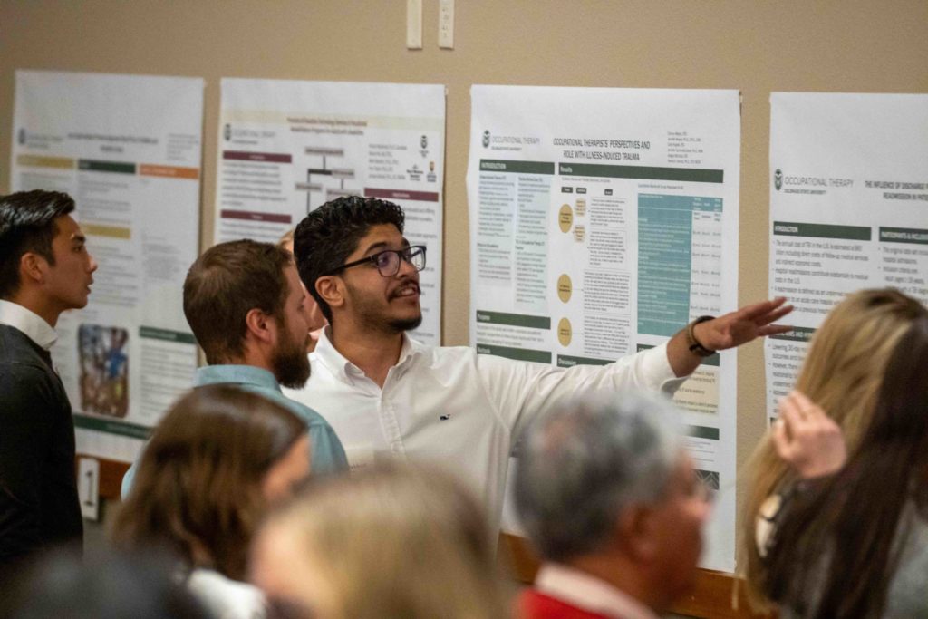 A student discussing his poster with a crowd