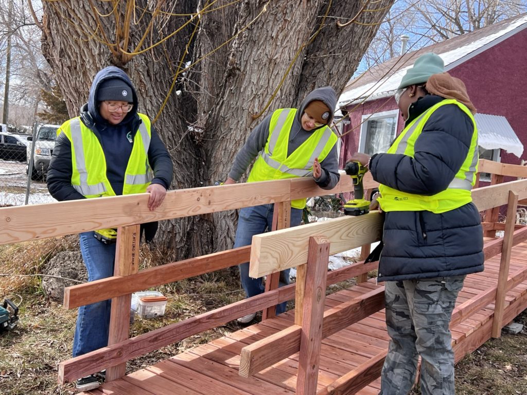 3 people working to construct wooden ramp rails