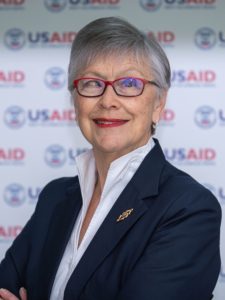 A woman in a suit in front of a USAID-branded backdrop