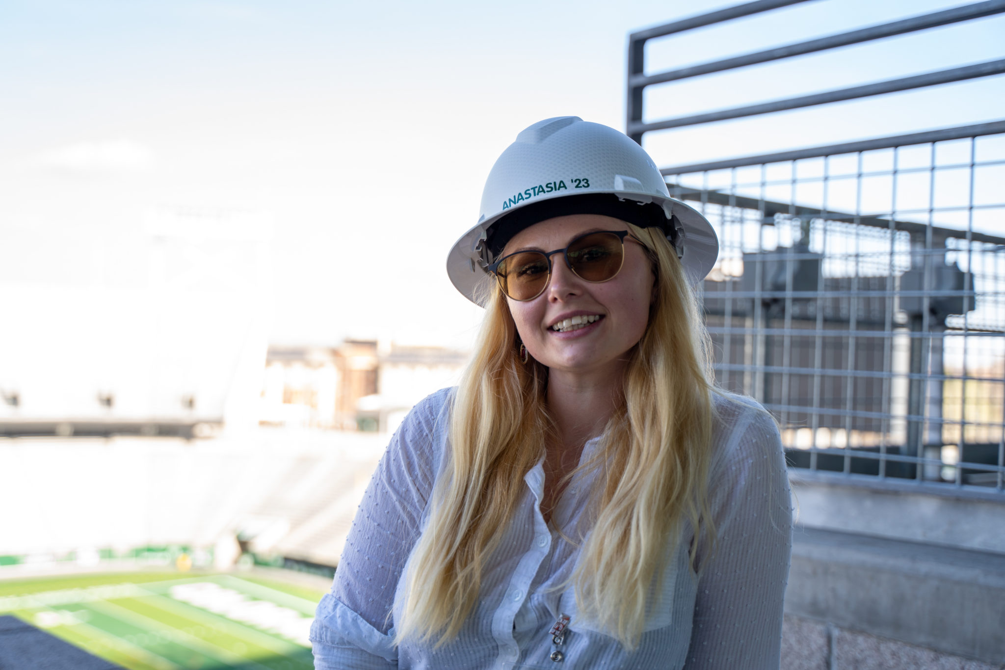 Anastasia Sanchez wearing a hardhat with the stadium football field behind her