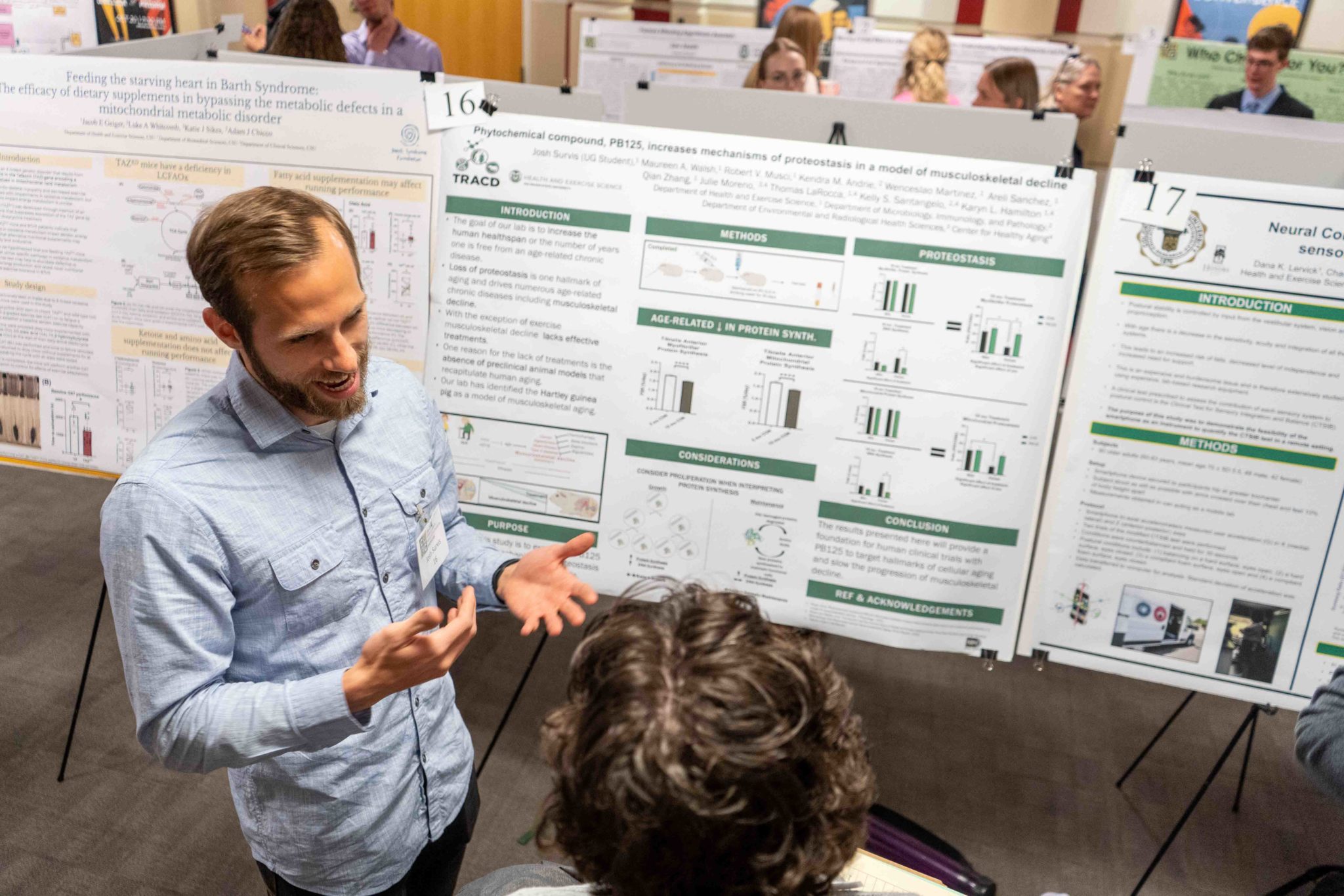 An undergraduate student explains his research poster to a symposium judge.