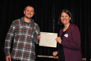 A faculty member presents an award certificate to a student