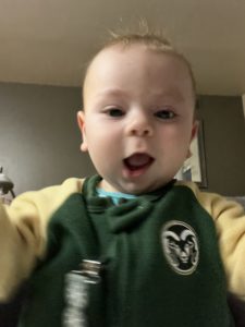 A happy baby wearing a CSU Rams shirt