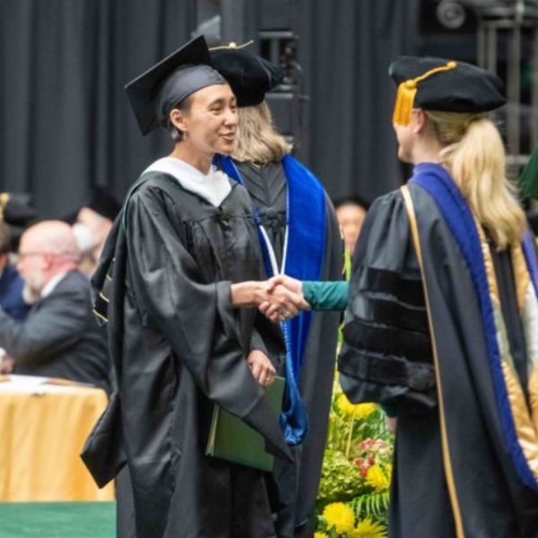 Larissa Cambel shakes hands with CSU President Amy Parsons as she walks across the stage at graduation.