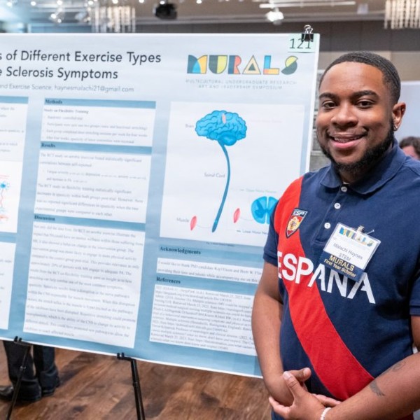 A student standing in front of his research poster