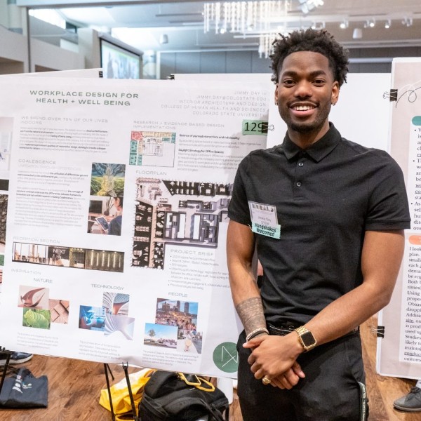 A student standing in front of their research poster