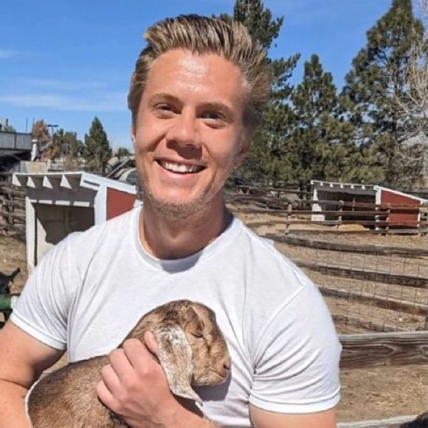 Nash Murath posing for a photo while holding a baby goat