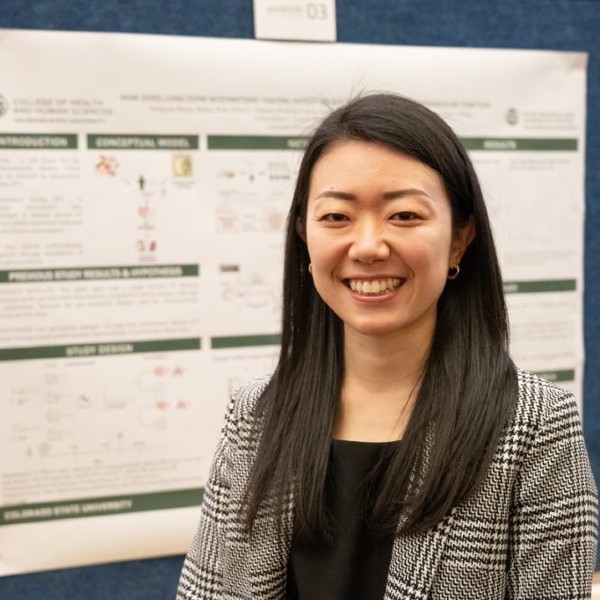 A student standing in front of her research poster