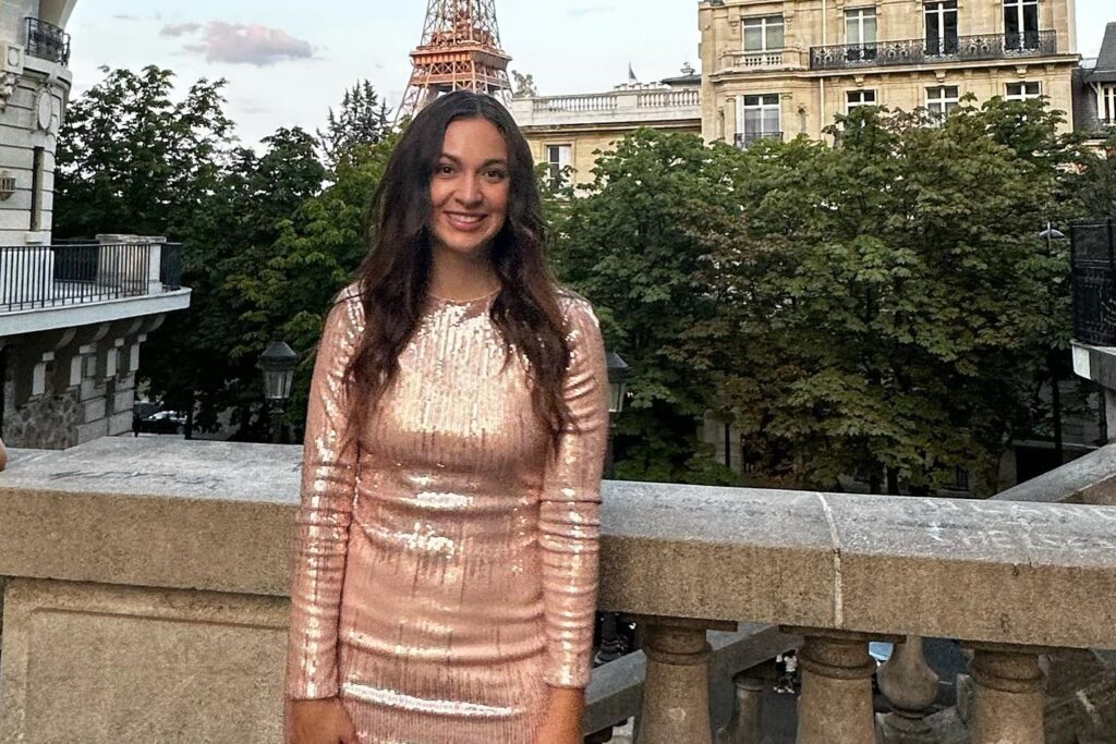 Natalie standing on a terrace in a sequined dress in front of the Eiffel Tower