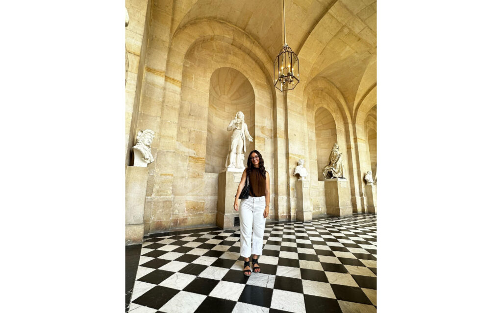 Natalie standing in front of a statue in the Palace of Versailles.