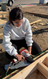 Julia Menezes with nail gun working on a framing project