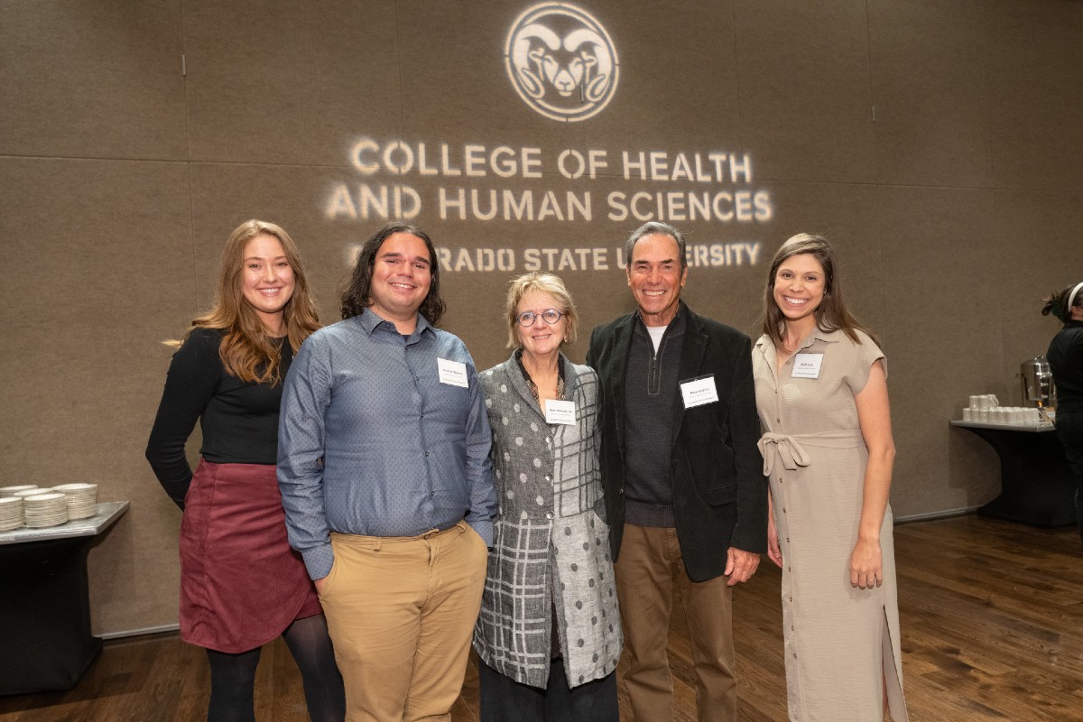 Five donors and students stand in front of a wall with the CSU College of Health and Human Sciences logo projected on it