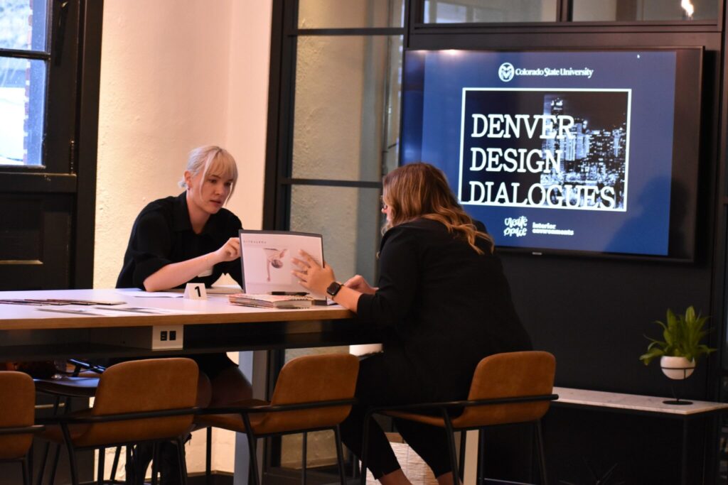a student shows an alumna and design professional her portfolio