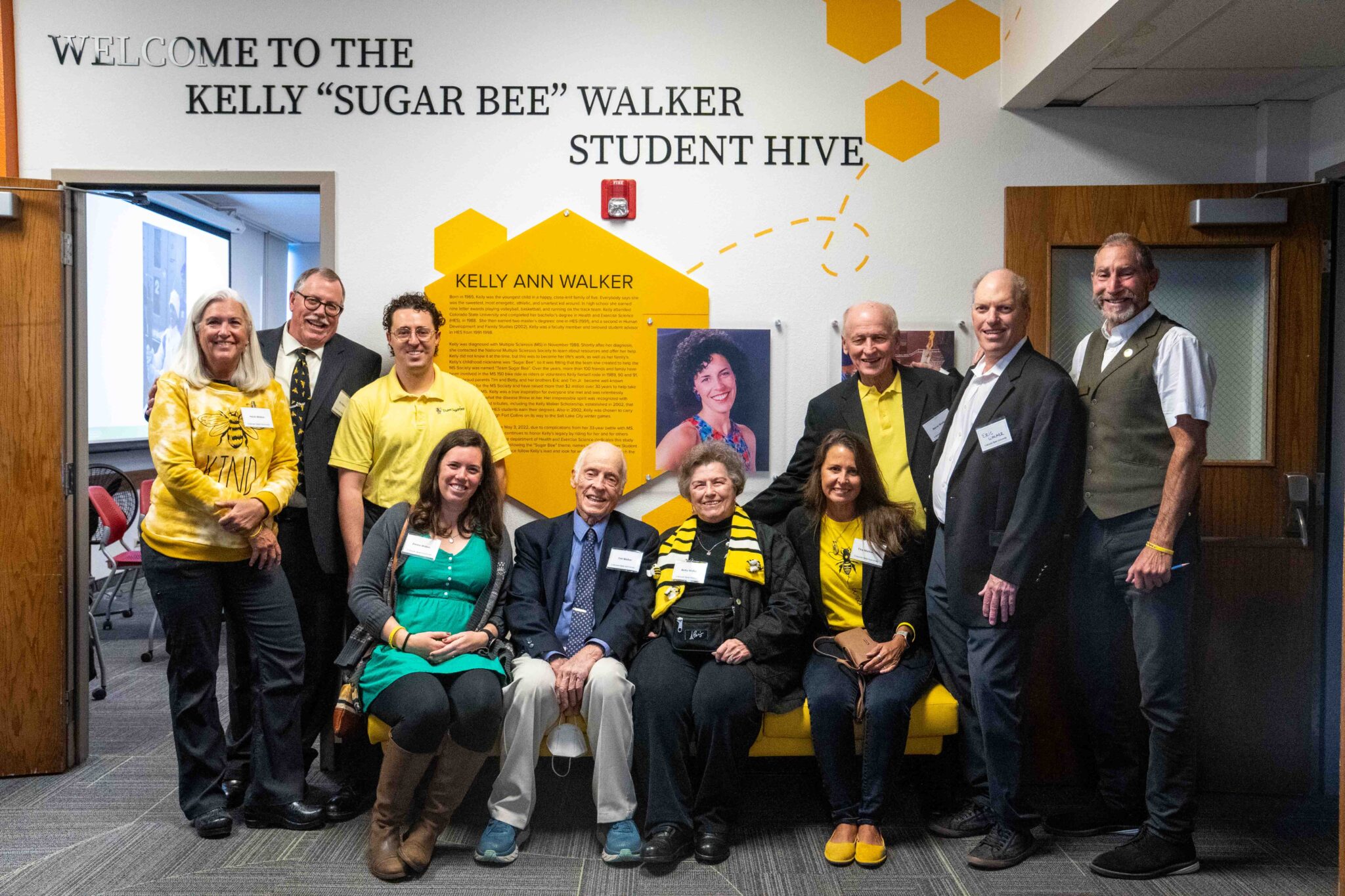 Multiple generations of Walker family members gather around a wall with yellow hexagons