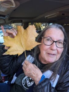 Elderly woman in car holding a yellow leaf