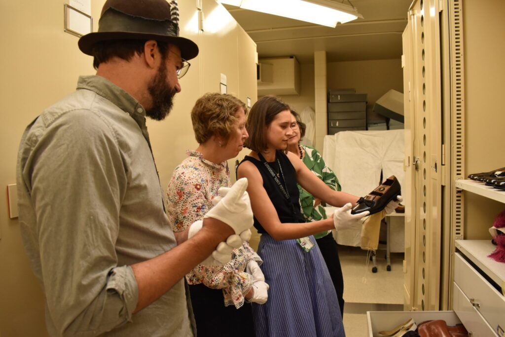 Dan Huling, Karen Hyllegard, and Doreen Beard look at a historic shoe held by Paula Alaszkiewicz