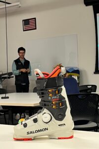 Dan Feeney, PhD from BOA fit systems presents to the students with a ski boot in the foreground that showcases the BOA rotating lace technology