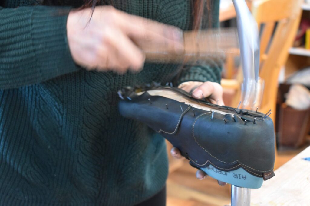Lida Aflatoony hammering leather into the sole of a shoe