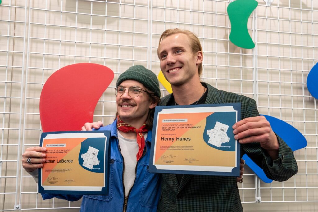Henry and Ethan stand together holding their award certificates