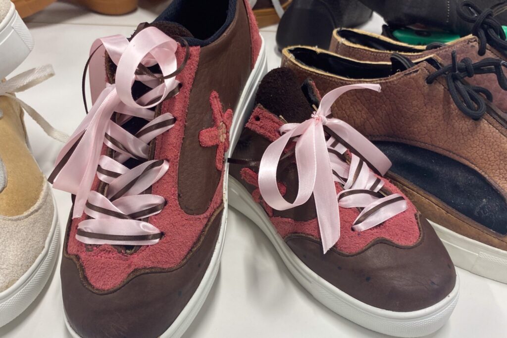 a shot of 2-3 pairs of shoes created by the students primarily featuring the pink shoes with floral appliques.