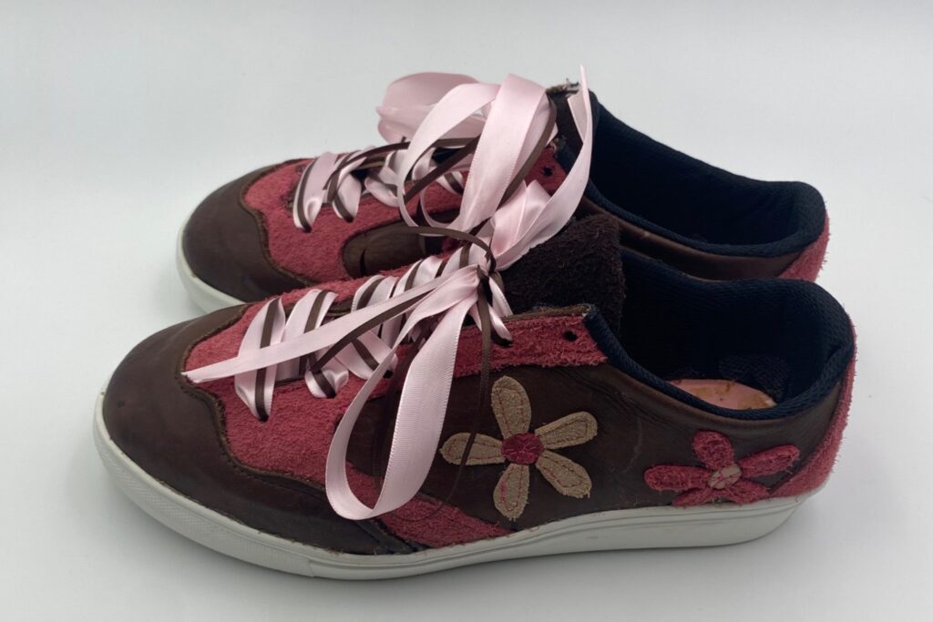 a sample of shoes made b the students with aplique leather creating flower patterns and pink laces