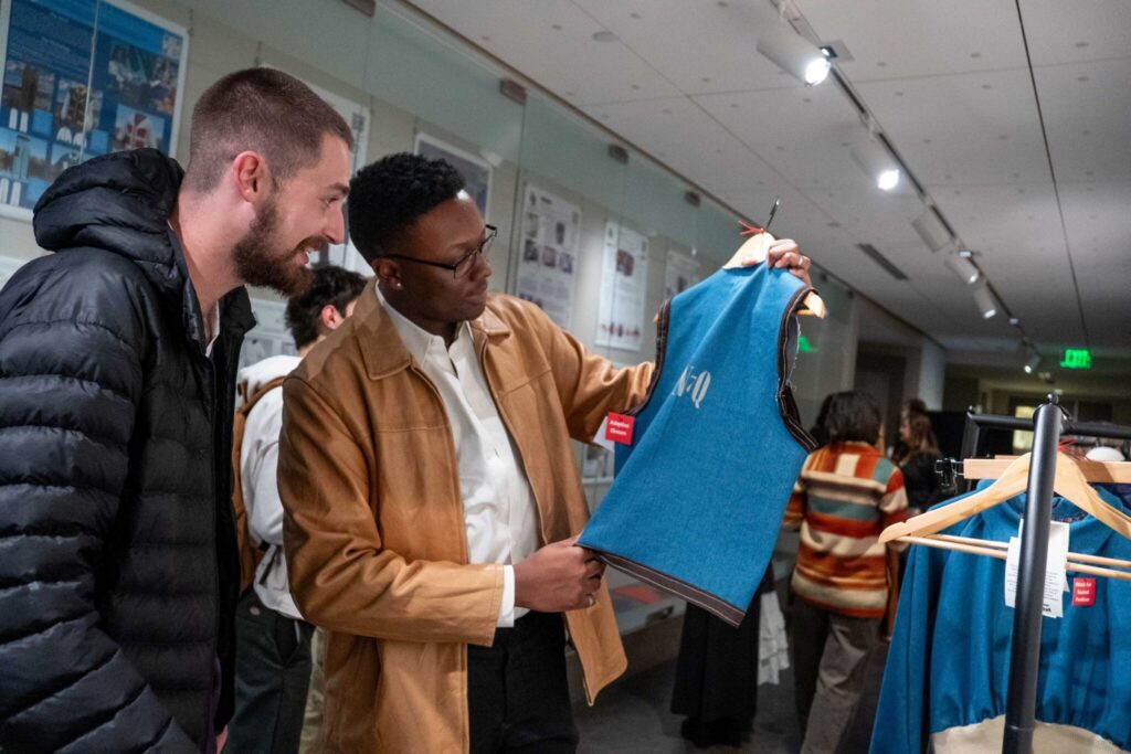 2 male students look at a vest prototype up close