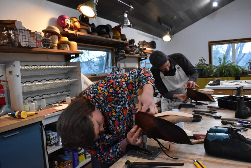 Kristen Morris and Dan Huling look at the underside of shoes as they construct them on a form