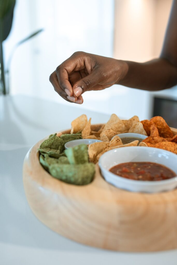 A hand poised over a bowl of chips and salsa