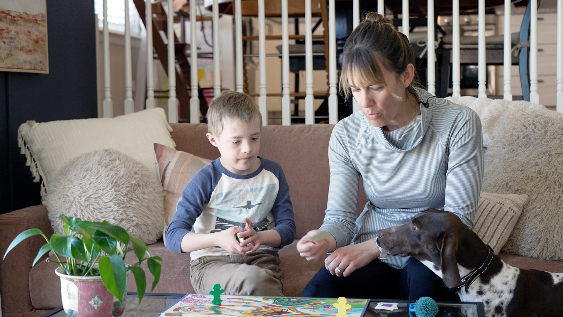Noah, the 9-year-old son of Elizabeth Jeub, sit in their Brighton living room playing Candyland while family dog Coco watches.