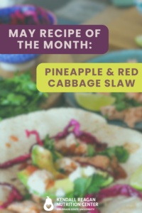 A graphic that reads "May recipe of the month, pineapple & red cabbage slaw, Kendall Reagan nutrition center Colorado State University." The background photo is a table with a plate of shrimp, a bowl of red cabbage shred and a plate with a taco full of shrimp, cabbage shreds and avocado.