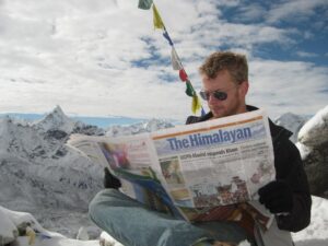 Moon reads the newspaper on top of a mountain in the Himalaya.