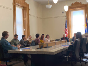 Students and representatives sit around a table in the capitol.