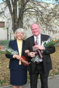 Vicky and Roy Buchan smile in formal attire with flowers.