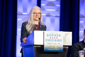 Heather Shea speaks at a podium during an ACPA conference.