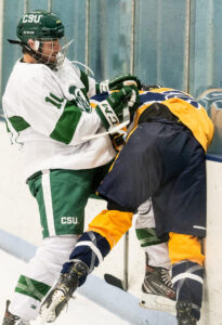 Two Hockey players battling each other, one in white and green and one in yellow and dark blue.