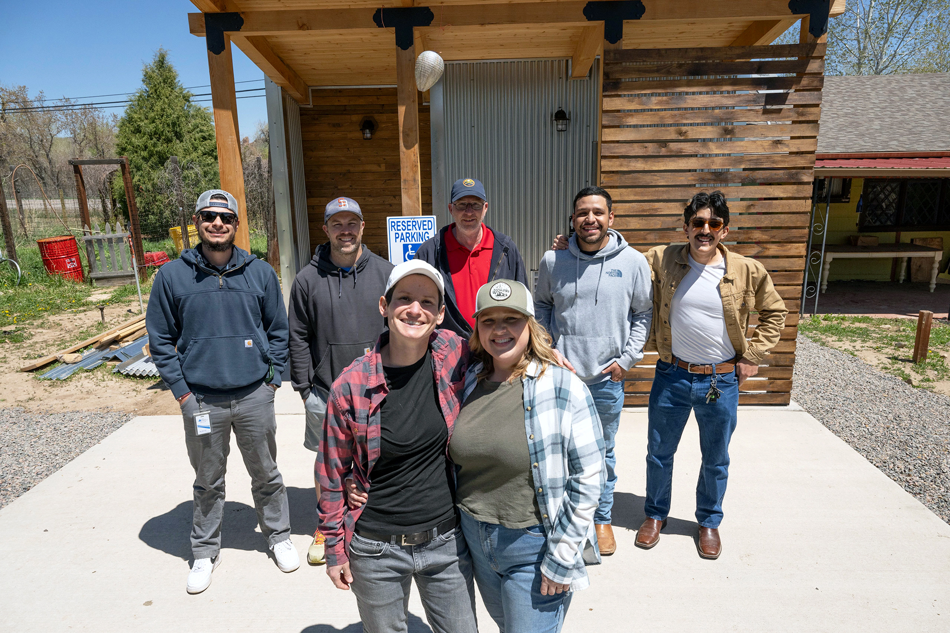 Wiley Acres owners Lauren and Alyssa Sturges stand in front of former CM Cares students and the new restroom built to be accessible in the background.