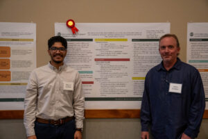 Rayyan Bukhari and James Graham standing in front of Bukhari's research poster board