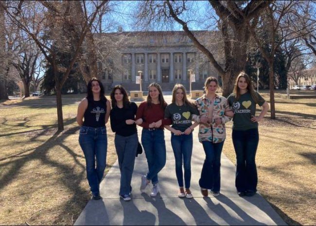 6 high school aged women stand next to each other on the CSU oval.
