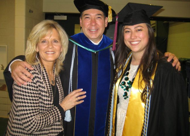 Ashley, Dawn and another faculty member wearing graduation robes smile with Ashley on her graduation day.