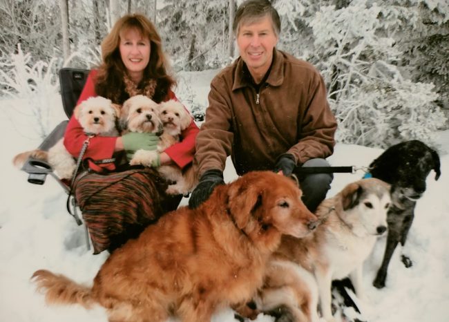 Michele and her husband, Chuck, are pictured outside in the snow with six dogs around them.